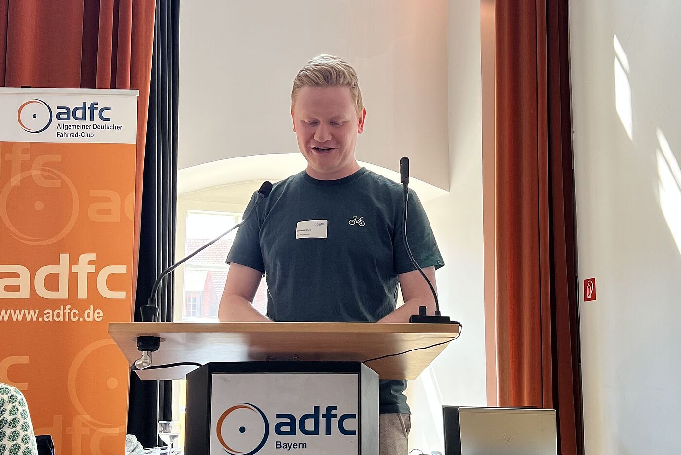 Als dritter im Bunde der Grußwortgeber*innen begrüßte der Vorsitzende des ADFC Regensburg, Benedikt Benz, die Versammlung und wünschte sich "mehr holländische Radinfrastruktur und mehr Schweizer Zuginfrastruktur" für Deutschland. Als dritter im Bunde der Grußwortgeber*innen begrüßte der Vorsitzende des ADFC Regensburg, Benedikt Benz, die Versammlung und wünschte sich "mehr holländische Radinfrastruktur und mehr Schweizer Zuginfrastruktur" für Deutschland.