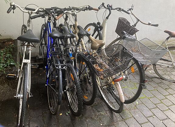 rraeder stehen zusammen gequetscht im Regen da kein Fahrradraum vorhanden ist.